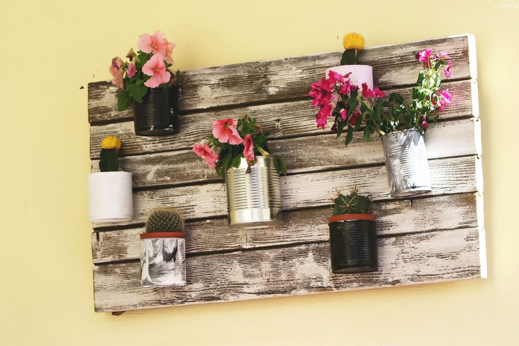 Décoration murale réalisée avec des planches en bois et des plantes dans des conserves